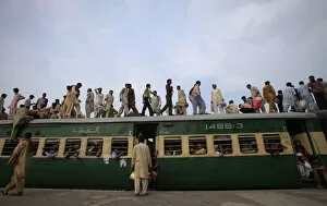 Images Dated 18th August 2012: Passengers climb aboard a carriage of a train at a railway station in Lahore
