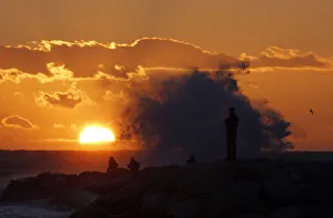 Passers-by look at a high wave hitting the waterfront at sunset in Marseille Passers-by look at a high wave hitting the waterfront at sunset in Marseille