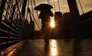 A pedestrian carries an umbrella as he walks over one of the Golden Jubilee Bridges in A pedestrian carries an umbrella as he walks over one of the Golden Jubilee Bridges in