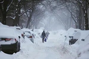 Pedestrians make their way along a snow covered street during a winter snow storm in Pedestrians make their way along a snow covered street during a winter snow storm in