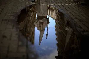 A penitent is reflected in a puddle of water after rain fell at the Humildad brotherhood A penitent is reflected in a puddle of water after rain fell at the Humildad brotherhood