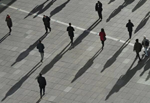 Images Dated 17th January 2018: People cast long shadows in the winter sunlight as they walk across a plaza in the