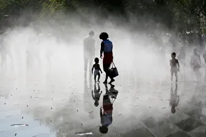 People gather near fountains of water as they cool off at the Miroir d'Eau People gather near fountains of water as they cool off at the Miroir d'Eau