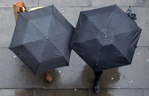 People shelter under umbrellas as they walk through central London People shelter under umbrellas as they walk through central London
