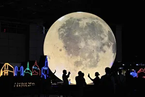People stand in front of a moon installation at Nanjing Road on the eve of the Mid-Autumn People stand in front of a moon installation at Nanjing Road on the eve of the Mid-Autumn
