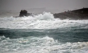 People standing on the Pointe de la Torch peninsula watch waves breaking on the Brittany People standing on the Pointe de la Torch peninsula watch waves breaking on the Brittany