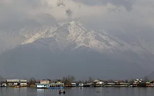 People travel in small boat on waters of Dal Lake on sunny day in Srinagar People travel in small boat on waters of Dal Lake on sunny day in Srinagar