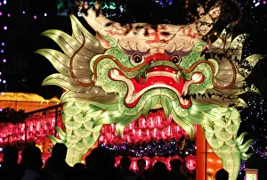 People walk besides a dragon-shaped lantern on display during Lantern Festival celebrations