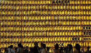 People walk in front of paper lanterns during the Mitama Festival at the Yasukuni People walk in front of paper lanterns during the Mitama Festival at the Yasukuni