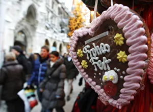 People walk past a gingerbread pastry reading happy celebration at a market in Munich People walk past a gingerbread pastry reading happy celebration at a market in Munich