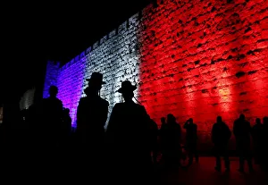 Rabbi Gallery: People walk past the walls of Jerusalems Old City lit in blue, white and red