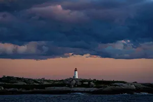 People walk on the rocks at the lighthouse at dusk in Peggys Cove People walk on the rocks at the lighthouse at dusk in Peggys Cove