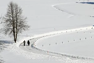 People take a walk along snow covered fields during sunny winter weather in Oberstdorf People take a walk along snow covered fields during sunny winter weather in Oberstdorf