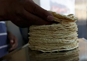 Person weighs a stack of freshly made corn tortillas at a tortilla factory in Mexico City Person weighs a stack of freshly made corn tortillas at a tortilla factory in Mexico City