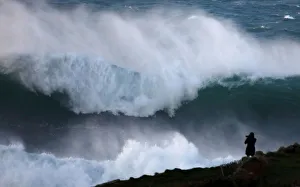 A photographer takes pictures of waves breaking on the Brittany coast at Audierne in A photographer takes pictures of waves breaking on the Brittany coast at Audierne in