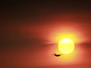 A plane flies past a setting sun near the Songshan airport in Taipei, Taiwan A plane flies past a setting sun near the Songshan airport in Taipei, Taiwan