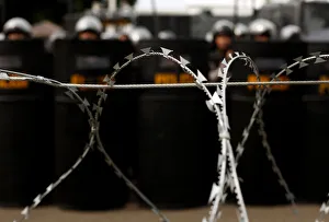 Indonesia Gallery: Policemen stand behind barbed wire in front of the presidential palace during a rally in
