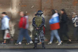 Protesters walk past an officer of the Russian National Guard during a rally against Protesters walk past an officer of the Russian National Guard during a rally against