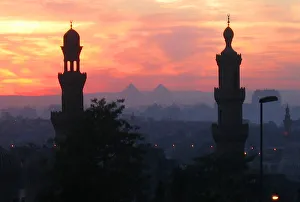 Pyramids of Giza appear between two minarets during a warm winter sunset in Cairo Pyramids of Giza appear between two minarets during a warm winter sunset in Cairo