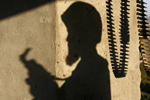 The shadow of an Afghan National Army soldier and bullets are cast on the wall of The shadow of an Afghan National Army soldier and bullets are cast on the wall of