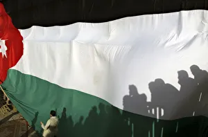 Shadows of people were cast on a large Jordanian national flag during a celebration to Shadows of people were cast on a large Jordanian national flag during a celebration to