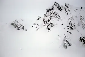 A snowboarder descends from a rough mountain slope towards Balea glaciar lake at Balea A snowboarder descends from a rough mountain slope towards Balea glaciar lake at Balea