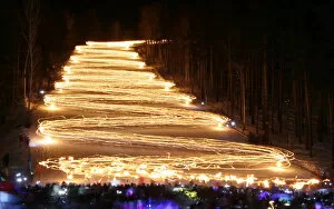 Related Images Gallery: Spectators watch skiers descending down from the slope while holding lit torches in the