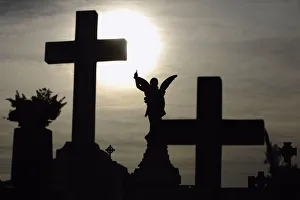 The sun is pictured behind a cross on a gravestone on the eve of All Saints Day The sun is pictured behind a cross on a gravestone on the eve of All Saints Day