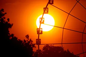 The sun is seen through the giant Ferris wheel at Place de la Concorde at sunset in Paris The sun is seen through the giant Ferris wheel at Place de la Concorde at sunset in Paris