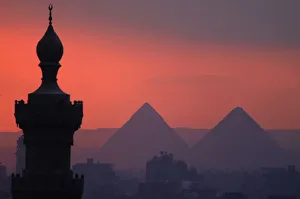 The sun sets on the minarets and the Great Pyramids of Giza in Old Cairo The sun sets on the minarets and the Great Pyramids of Giza in Old Cairo