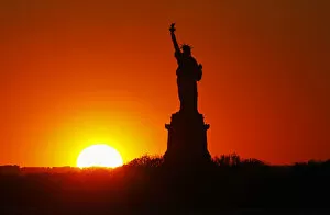 Images Dated 27th May 2013: The sun sets behind the Statue of Liberty in New York