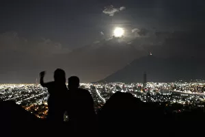 Images Dated 11th August 2014: A supermoon rises while a couple takes a photo in Monterrey