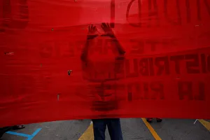 A supporter of the Communist party uses a scissors to make holes on a banner as he takes A supporter of the Communist party uses a scissors to make holes on a banner as he takes