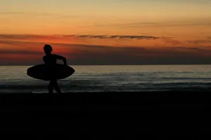 Images Dated 5th January 2018: A surfer carries his board off the beach after surfing in Cardiff, California