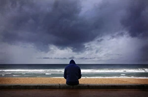 A surfer looks at waves as storm clouds move in from Pacific Ocean at Sydneys Manly