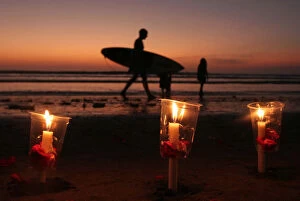 Indonesia Gallery: A surfer walks past candles during a commemoration of the 2002 Bali bombing in Kuta