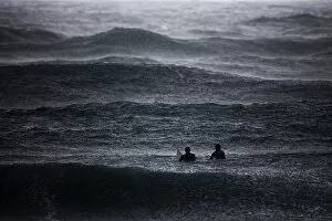 Images Dated 27th January 2012: Surfers wait to catch a wave in the Mediterranean Sea as it rains in Israels southern