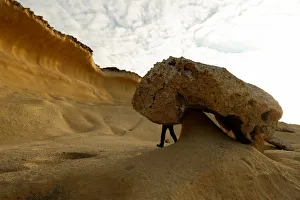 A tourist hikes past the so-called Mushroom Rock , formed by years of weathering A tourist hikes past the so-called Mushroom Rock , formed by years of weathering