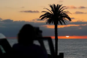 A tourist takes a picture of the setting sun at Moonlight Beach in Encinitas, California A tourist takes a picture of the setting sun at Moonlight Beach in Encinitas, California