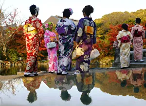 Tourists, dressed in traditional Japanese kimonos, stand in a park in Kyoto Tourists, dressed in traditional Japanese kimonos, stand in a park in Kyoto