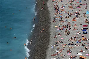 Tourists sunbathe and swim at the beach during a sunny summer day in Nice, southeastern Tourists sunbathe and swim at the beach during a sunny summer day in Nice, southeastern