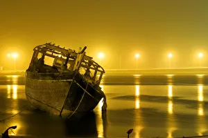 A traditional fishing boat lies at the sea-shore due to bad weather and low-tides A traditional fishing boat lies at the sea-shore due to bad weather and low-tides