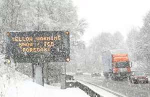 Traffic passes a road sign warning of adverse weather conditions on the A9 near