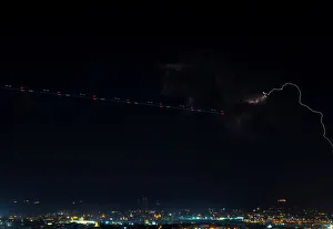 A trail left by a plane is seen near a lightning storm, seen from Mdina A trail left by a plane is seen near a lightning storm, seen from Mdina