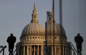UK Landmarks Prints: A pedestrian is reflected in glass as he walks towards St Pauls Cathedral in