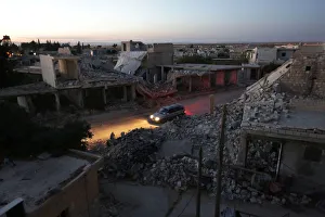 A vehicle drives past damaged buildings in the northern Syrian rebel-controlled town of A vehicle drives past damaged buildings in the northern Syrian rebel-controlled town of
