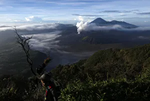 Indonesia Gallery: A visitor walks as Indonesias Mount Bromo volcano spew smoke next to Mount Semeru