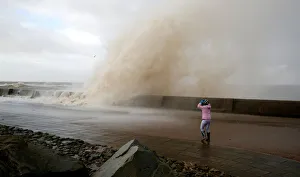 A walker watch the waves breaking in New Brighton, on the coast of the Wirral peninsula A walker watch the waves breaking in New Brighton, on the coast of the Wirral peninsula