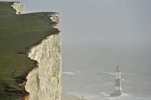 Walkers look out over Beachy Head lighthouse and heavy seas in the English Channel Walkers look out over Beachy Head lighthouse and heavy seas in the English Channel