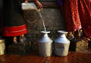 A woman fills her pot with water after pulling it out from an almost dried well in A woman fills her pot with water after pulling it out from an almost dried well in